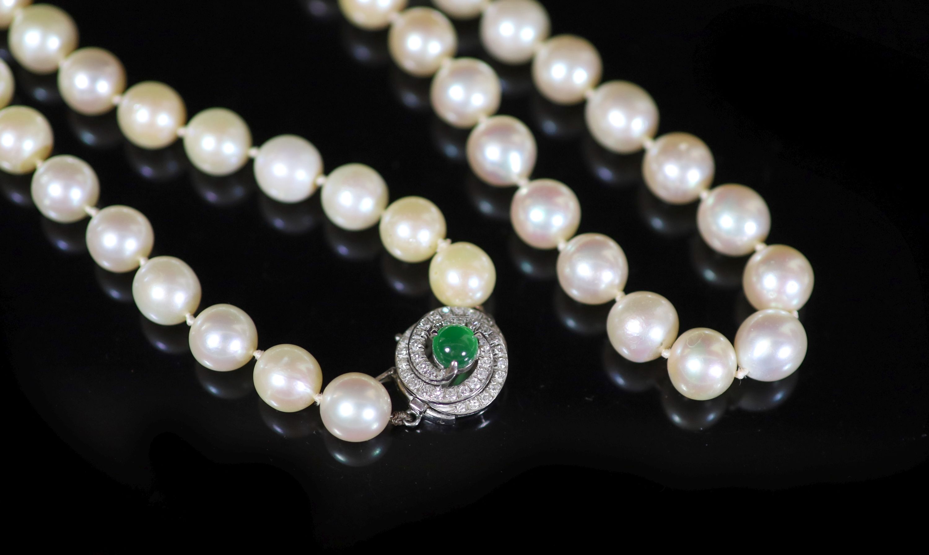 A single strand uniform cultured pearl necklace with diamond and cabochon emerald set clasp,